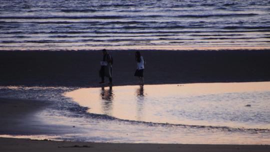 傍晚沙滩上散步的男女情侣
