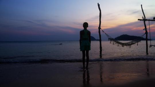女孩在日落海滩边站立