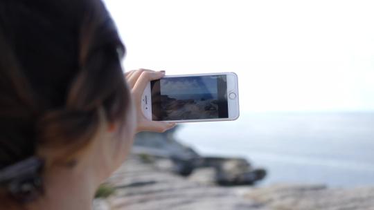 一个女人用手机拍摄海洋景观