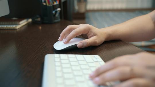 一个女人在家工作时控制电脑鼠标的特写镜头