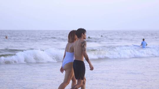 一对情侣在海滩上散步，手牵着手