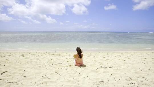 海滩上端坐着的女孩背景特写
