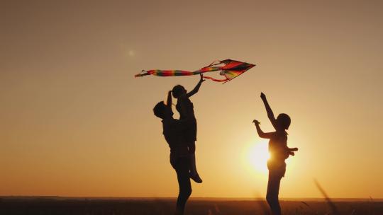 幸福的一家人三口放风筝 看夕阳晚霞