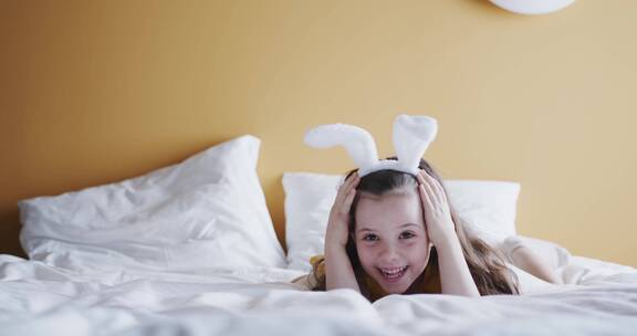 戴着复活节兔子发带的女孩趴在床上
