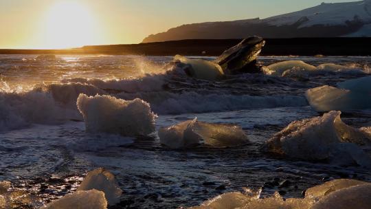 夕阳下海浪拍打冰山