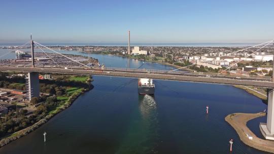城市航拍远洋货轮穿过跨海大桥进入海港港口