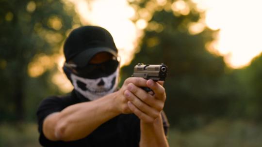 一个戴着手帕和太阳镜的男人正准备开枪，特写。慢动作