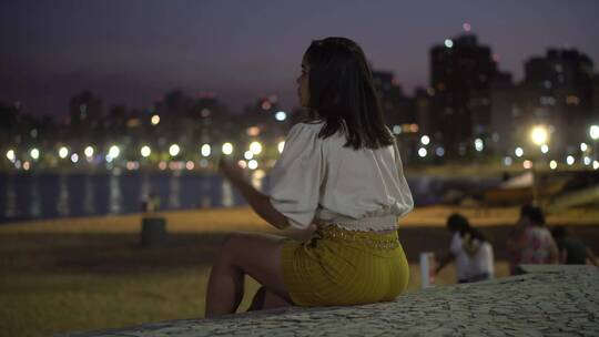 女人坐在海边看城市风景