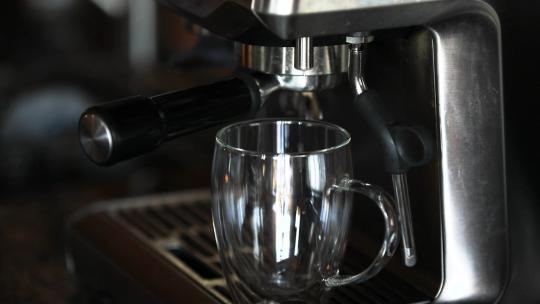 咖啡机将热水注入玻璃杯中的特写