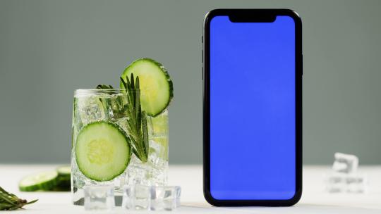 黄瓜切片在杯中和旁边的手机的画面特写