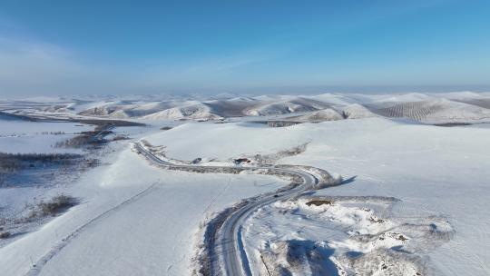 冬季丘陵山区蜿蜒穿行在雪野中的道路