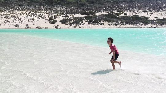 男孩在海滩的水中奔跑