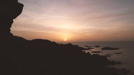 从岩石海岸线上看地平线上的日落