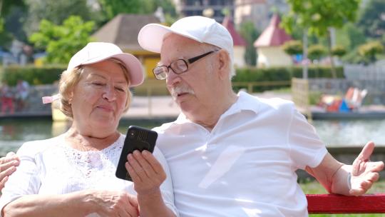 老年夫妻正在公园里用玩手机