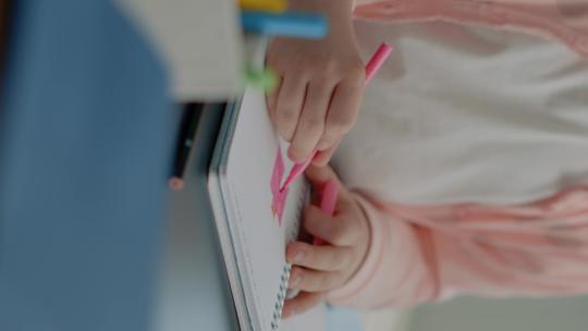 幼儿在笔记本上使用彩色铅笔的垂直视频特写