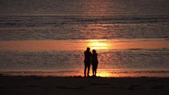 金色海面海滩上看落日一对恋人