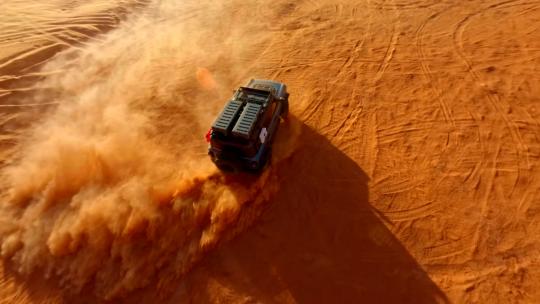 FPV航拍沙漠沙丘上行驶的越野车尘土飞扬