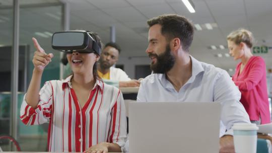 在办公室使用虚拟现实耳机让不同的男性和女性商业同事开心