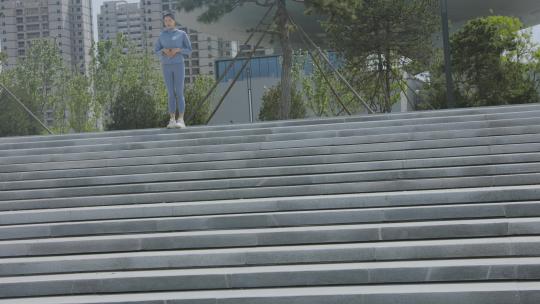 穿着运动装公园台阶上跑步的年轻女性