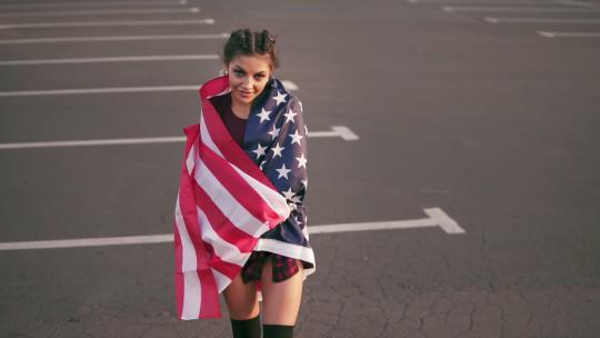 披着美国国旗的女孩在路上