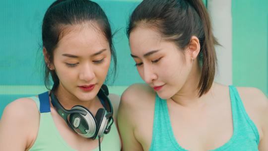两位运动女孩坐着休息听音乐