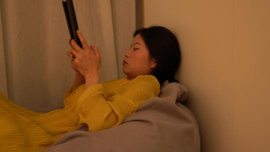 4K独居女性无聊躺在懒人沙发玩平板电脑视频素材模板下载