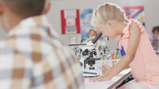 女孩在上课时用显微镜