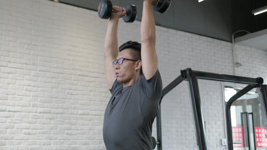 男子在健身房使用哑铃进行肩部训练视频素材模板下载