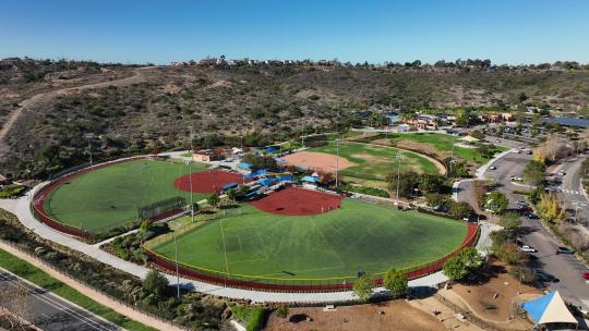 无人机从右向左旋转，捕捉加利福尼亚州卡尔斯巴德阿尔加北公园的足球和棒球场