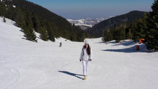 年轻女子走在雪山的滑雪道上