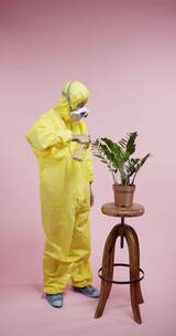 一名男子穿着全套防护服和防毒面具给植物浇水竖屏