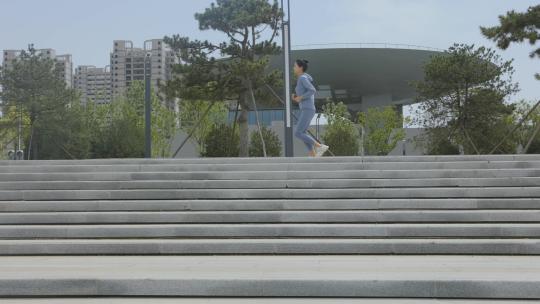 穿着运动装公园台阶上跑步的年轻女性